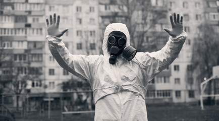 Centered black and white snapshot of a man, standing in front of a high block of flats, showing...