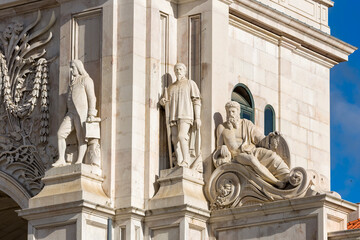 Obraz premium two seated statues at the base of Arco da Rua Augusta in Lisbon