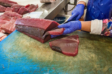 cut a slice of a red tuna in fish market of Olhao, Algarve, Portugal