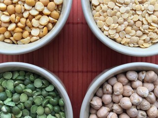 Round bowls with legumes, peas, chickpeas and lentils on a red background. A bowl of food on a plate. High quality photo