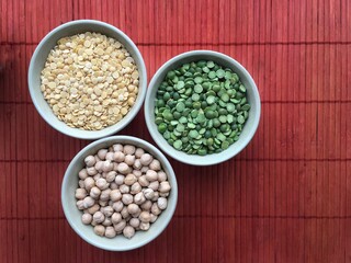 Round bowls with legumes, peas, chickpeas and lentils on a red background. A bowl of food on a plate. High quality photo