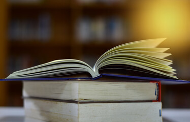 Open Book on wood table and blurred bookshelf in the library, education background, back to school concept.