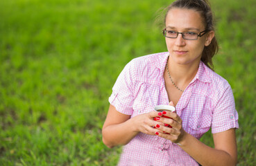 Woman holding a cup of coffee outside.