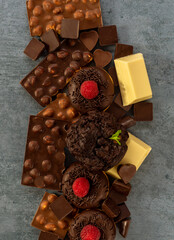 Assortment of white, dark, and milk chocolate with nuts, muffins, donuts. World Chocolate Day concept.