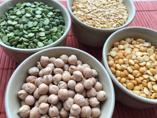 Round bowls with legumes, peas, chickpeas and lentils on a red background. A bowl of food on a plate. High quality photo
