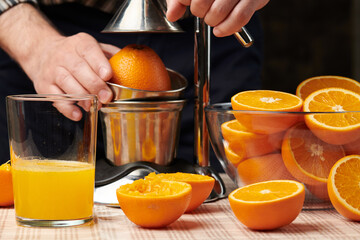 Squeezing an orange with a manual press, close view, making a glass of fresh. Fresh oranges on a...