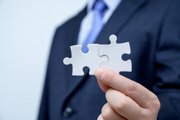 Businessman showing a jigsaw puzzle piece. Business and teamwork concept.