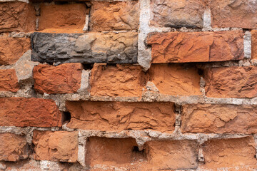 A stone wall in front of a brick building