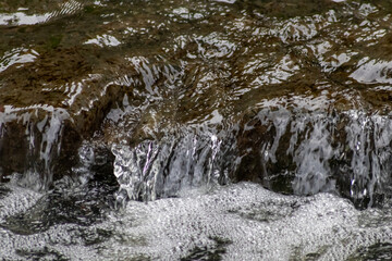 Calm floating creek with crystal clear water and rocks of a natural little dam or adventure hiking...