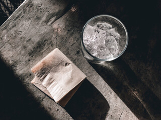 mash ice in the clear glass on cement table. And a napkin beside this clear glass.