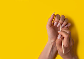Close-up of a woman makes herself a manicure on a yellow background, top view
