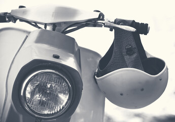 Old scooter with helmet and headlamp, monochrome colors. Vintage motorbike in retro style.