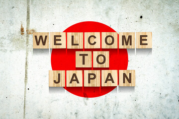 Obraz premium Welcome to Japan. The inscription on wooden blocks on the background of the flag of Japan. Travel.