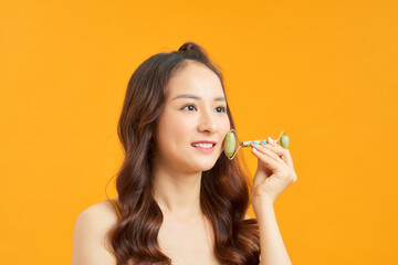Beautiful Asian woman uses jade roller to massage her face