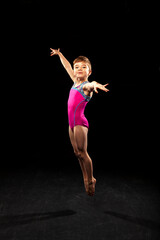 Fototapeta premium Young gymnast posing on a black background. 