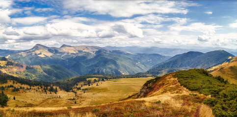 Mountains landscape with yellow grass scenic outdoor view, autumn rural day with cloudy sky. Adventure, mountain hiking. Beautiful moody light. Panoramic view background