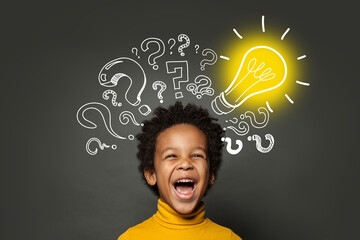 Laughing child boy student with lightbulb and question marks. Brainstorming and idea concept