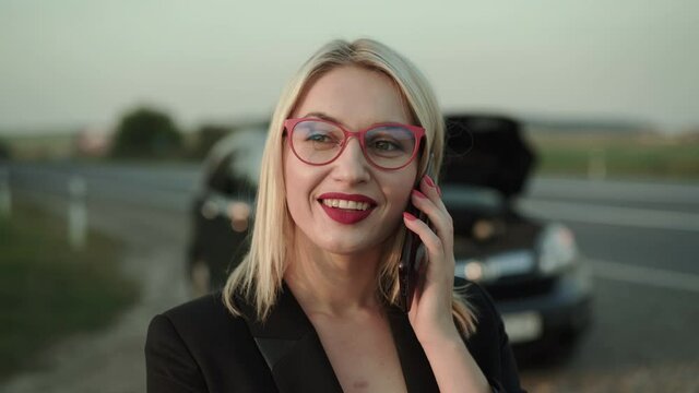 Beautiful blonde receives the call and talks with joy near a broken car