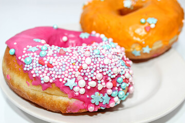 Two delicious donuts on a plate decorated with decorative sprinkles.