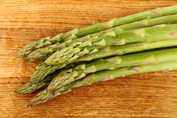 Fresh green washed asparagus on wooden board