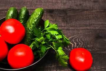 Seasonal vegetables on a plate: tomatoes, cucumbers, green onion, parsley. Organic vegetable from farm market. Vegan healthy food.