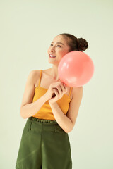 Portrait of attractive lovely gilr holding air balloon against light background.