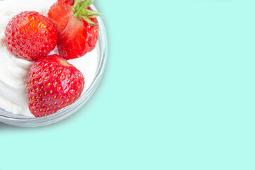 Sweet dessert with strawberries on a turquoise background. Whipped cream with strawberry arrangement in the corner. Copy space. Blank for menus, postcards, posters, advertising, etc.