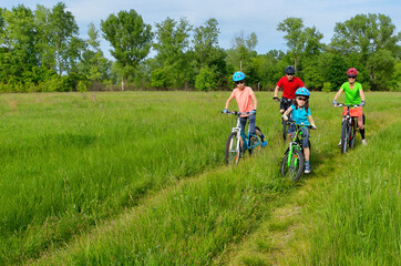 Naklejka premium Szczęśliwa rodzina na rowerach, wiosenna jazda na rowerze na świeżym powietrzu z dziećmi