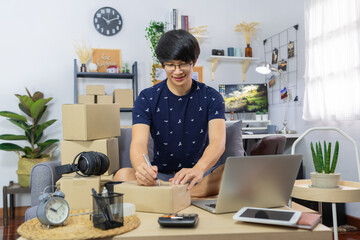small business asian man entrepreneur preparing parcels packing cardboard box for delivery