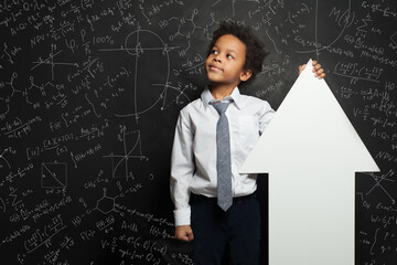 Smart black child student boy holding white empty banner arrow on chalkboard background with...