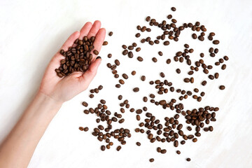 Coffee beans in hand on white background.