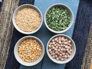 Round bowls with different legumes, peas, chickpeas and lentils on a colored tablecloth. Place for text. High quality photo