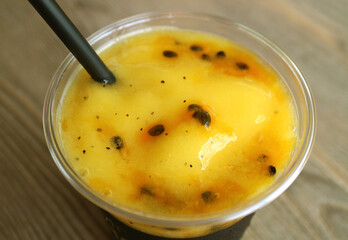 Closeup a Glass of Mouthwatering Fresh Passion Fruit with Mango Smoothie on Wooden Table