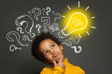 Thinking child boy on black background with light bulb and question marks. Brainstorming and idea...