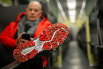 Shoe sole close-up, a man sitting in a train  and holding a telephone in his hands,public transport
