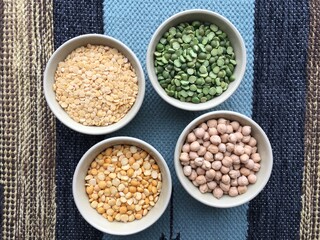 Round bowls with different legumes, peas, chickpeas and lentils on a colored tablecloth. Place for text. High quality photo