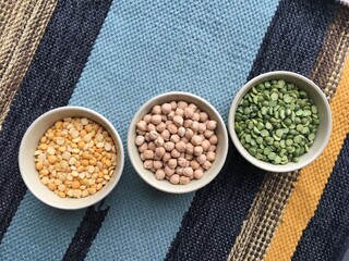 Round bowls with different legumes, peas, chickpeas and lentils on a colored tablecloth. Place for text.. Place for text. High quality photo