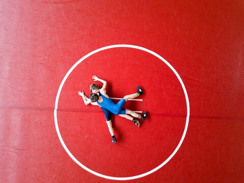 Aerial View Of Two Wrestlers Competing On A Red Wrestling Mat. 