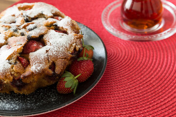 The cake with strawberry on the red background.