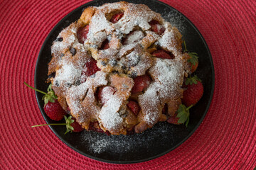 The cake with strawberry on the red background.