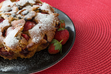 The cake with strawberry on the red background.