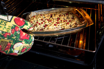 a hand in a baking glove takes out a delicious home-made berry pie from the oven.