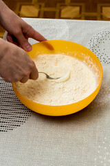 making dough for pancakes. kneading dough with female hands.