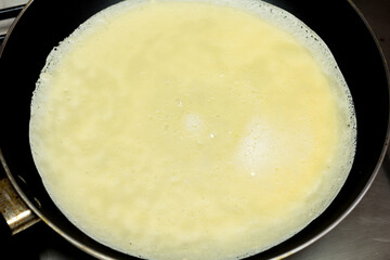 cooking pancakes in a pan on a gas stove. female hand pours the batter into the pan.