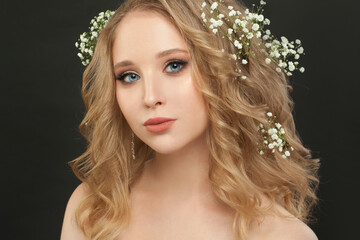 Fototapeta premium Lovely girl with blonde curly hair and flowers, beautiful face closeup