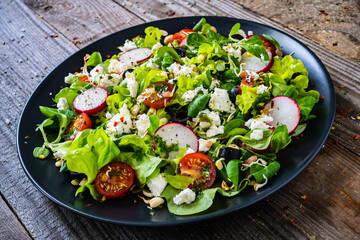 Fresh Greek salad - feta cheese, cherry tomatoes, lettuce and onion wooden table
