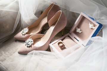 Elegant wedding accessories of an attractive bride. Wedding rings, shoes, bridal bouquet, floral arrangements, veil. Copy space for text. Background for greeting card or invitation.