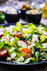 Fresh Greek salad - feta cheese, cherry tomatoes, lettuce and onion wooden table
