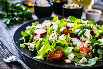 Fresh Greek salad - feta cheese, cherry tomatoes, lettuce and onion wooden table
