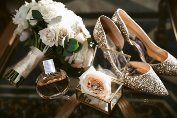 Elegant wedding accessories of an attractive bride. Wedding rings, shoes, bridal bouquet, floral arrangements, veil. Copy space for text. Background for greeting card or invitation.